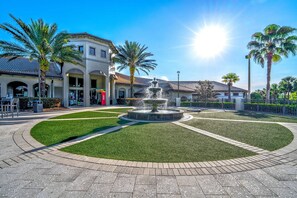 A fountain surrounded by a circular lawn with a building in the background. - Resort Access Pool Sleeps 10 Themed Rooms (Davenport)
