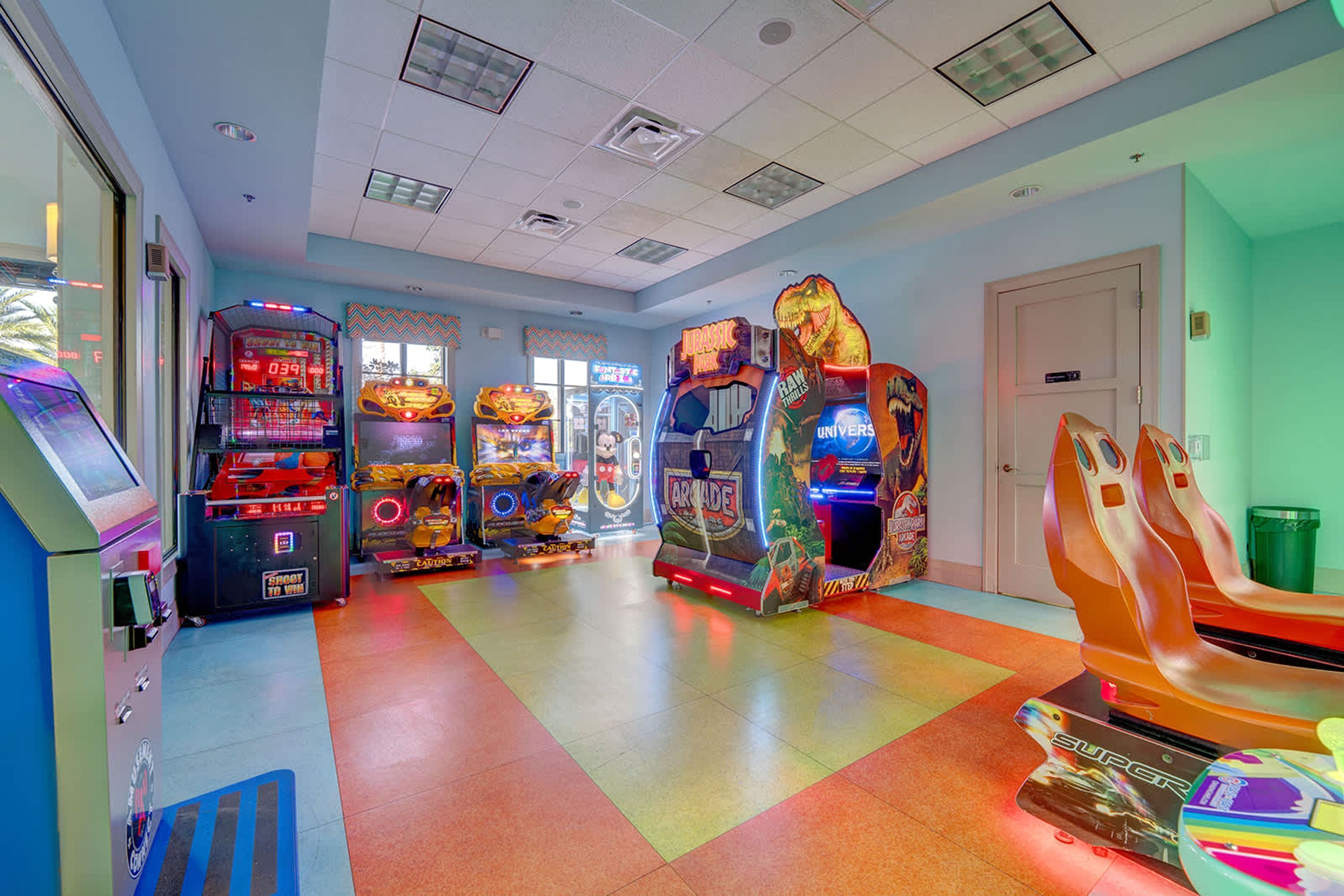An arcade room with various gaming machines, a trash bin, and a door.