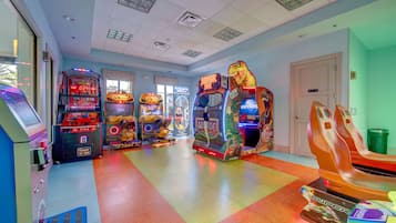 An arcade room with various gaming machines, a trash bin, and a door.