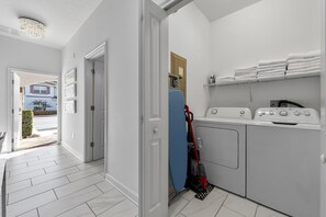 A laundry room with a washing machine, dryer, and stacked towels. - Resort Access Pool Sleeps 10 Themed Rooms (Davenport)