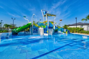 Um parque aquático com piscina, toboáguas e uma fonte de água.