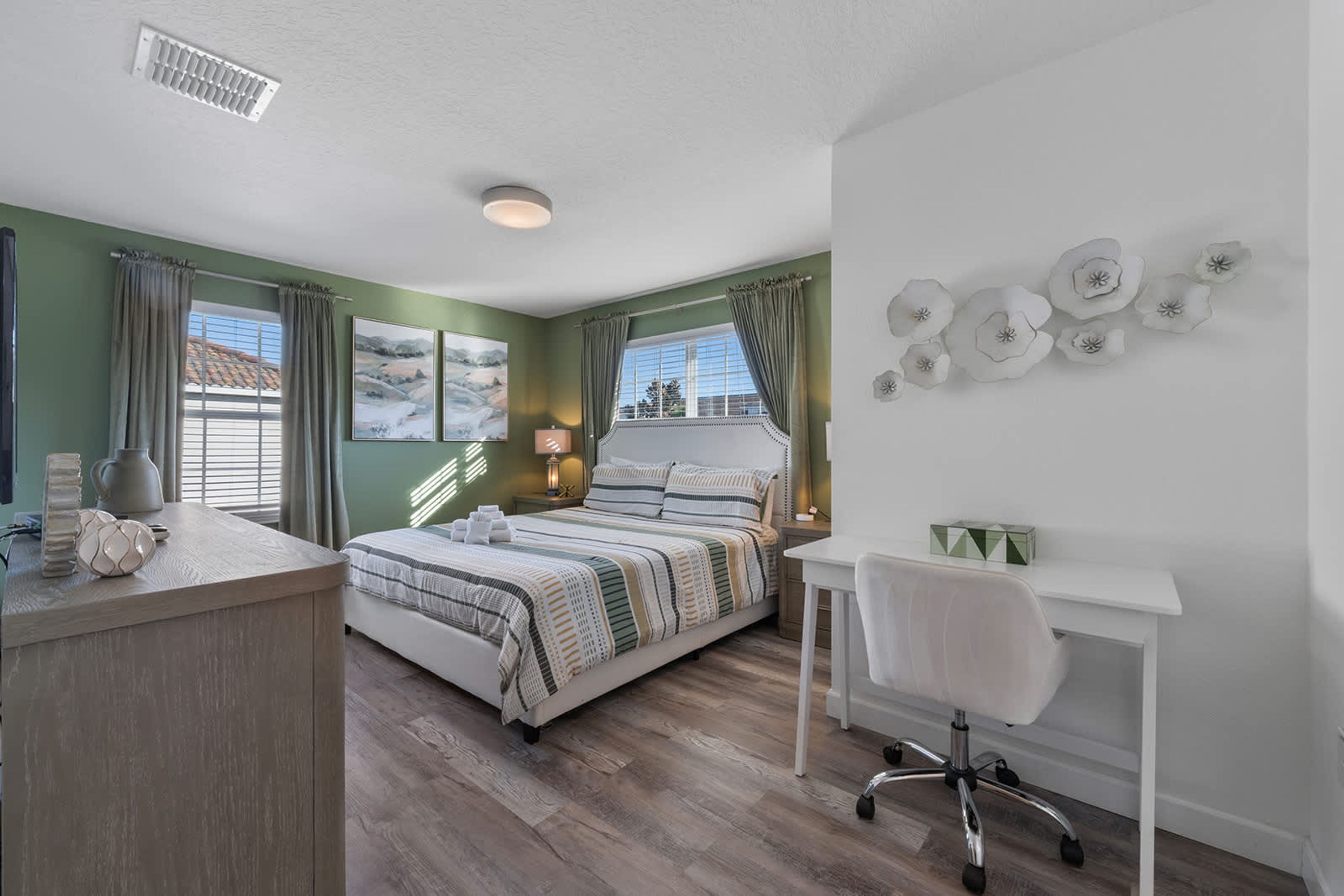 Une chambre à coucher comprenant un lit, un bureau, une chaise et un mur décoré d’assiettes.