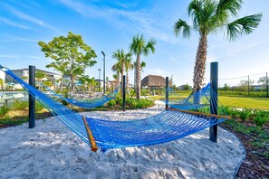 A hammock set up on a sandy area with palm trees and a building in the background. - Resort Access Pool Sleeps 10 Themed Rooms (Davenport)