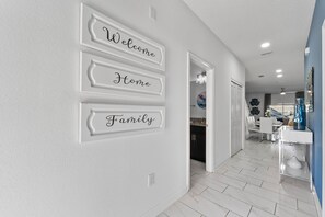 A hallway with a welcome sign, a kitchen area, and a dining space. - Resort Access Pool Sleeps 10 Themed Rooms (Davenport)