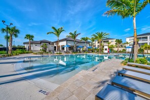 A swimming pool with lounge chairs and palm trees, surrounded by buildings with balconies. - Resort Access Pool Sleeps 10 Themed Rooms (Davenport)