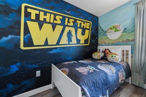 A bedroom with a Star Wars themed wall mural, a bed with a galaxy print bedspread, and a wall socket. - Resort Access Pool Sleeps 10 Themed Rooms (Davenport)