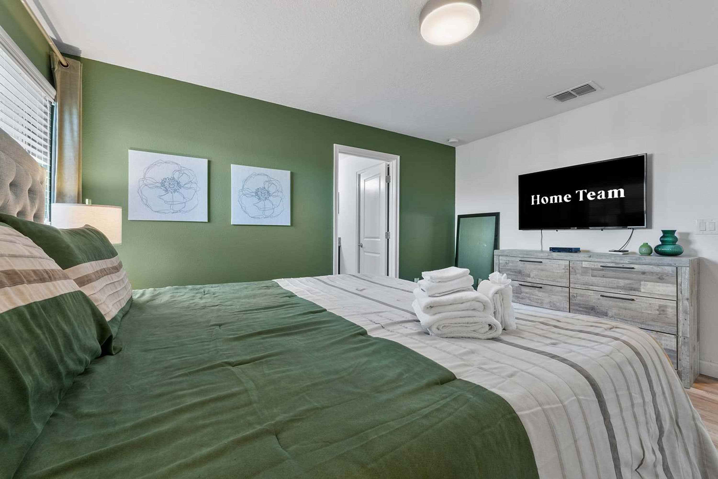 Ein Schlafzimmer mit einem Bett, einem Fernseher und Kunstwerken an der Wand.