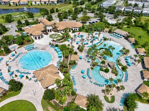 Vista aérea de un complejo turístico con varias piscinas, tumbonas y una fuente central.