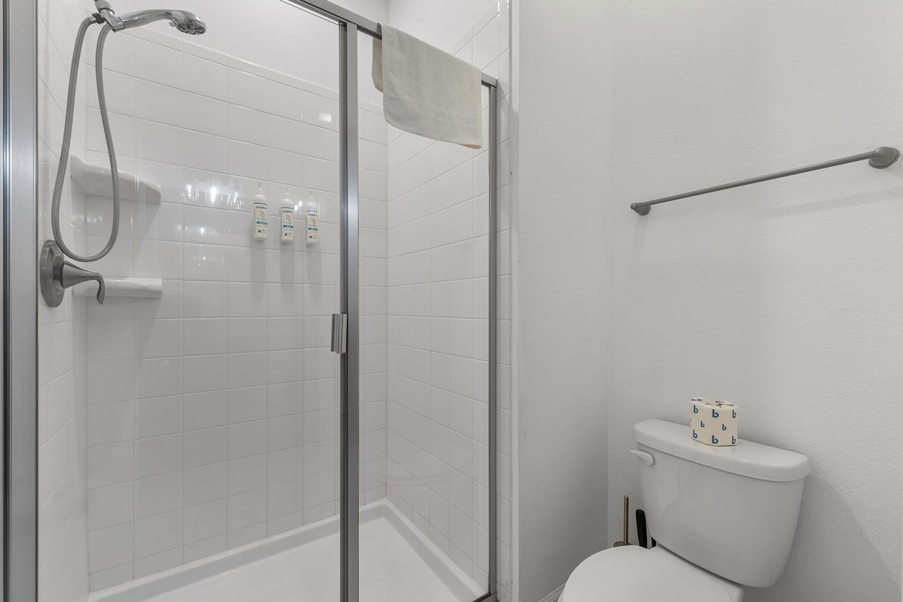 Ein modernes Badezimmer mit Duschkabine aus Glas, Toilette und Handtuchhalter.