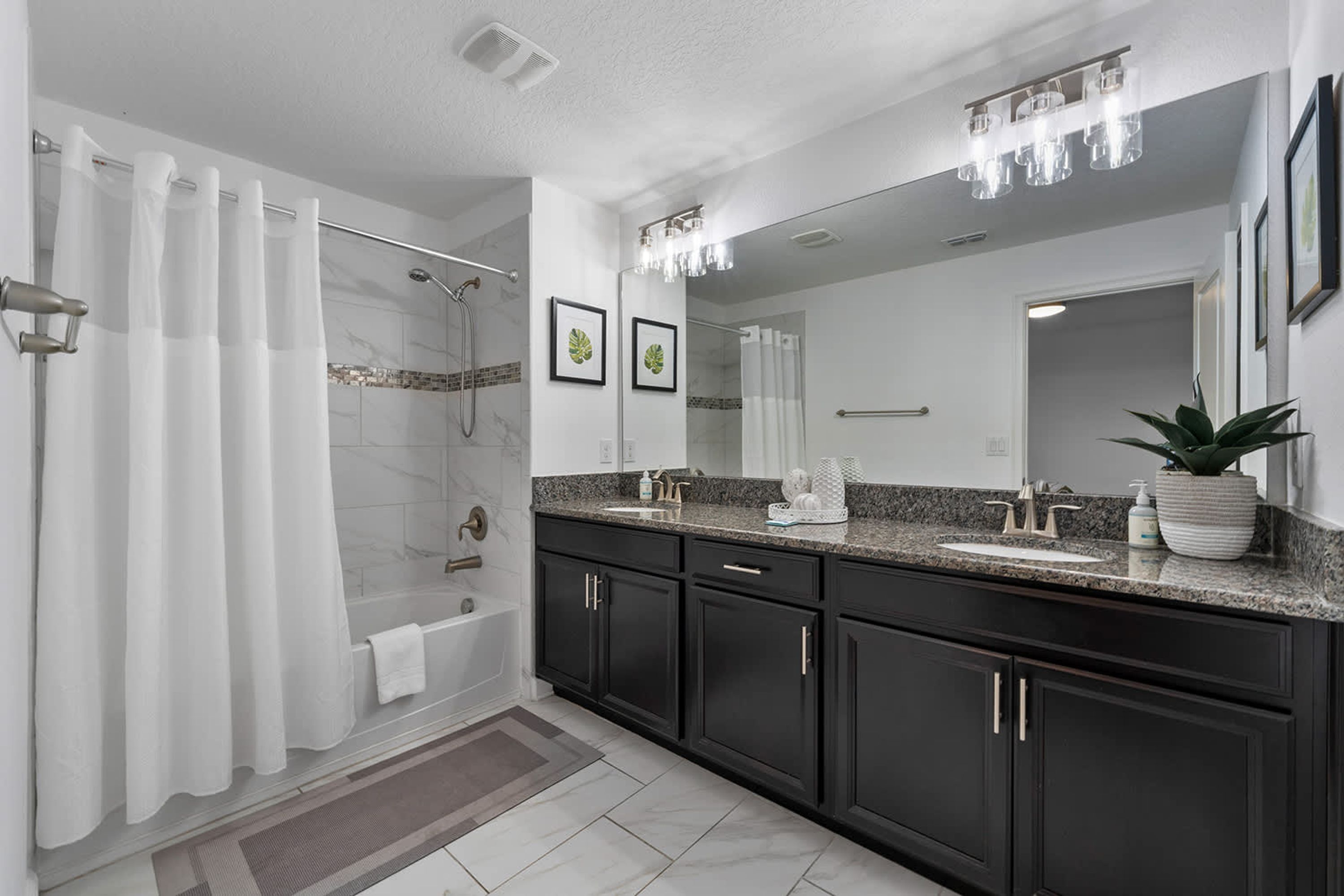 A modern bathroom with a walk-in shower, a large mirror, and a granite countertop.