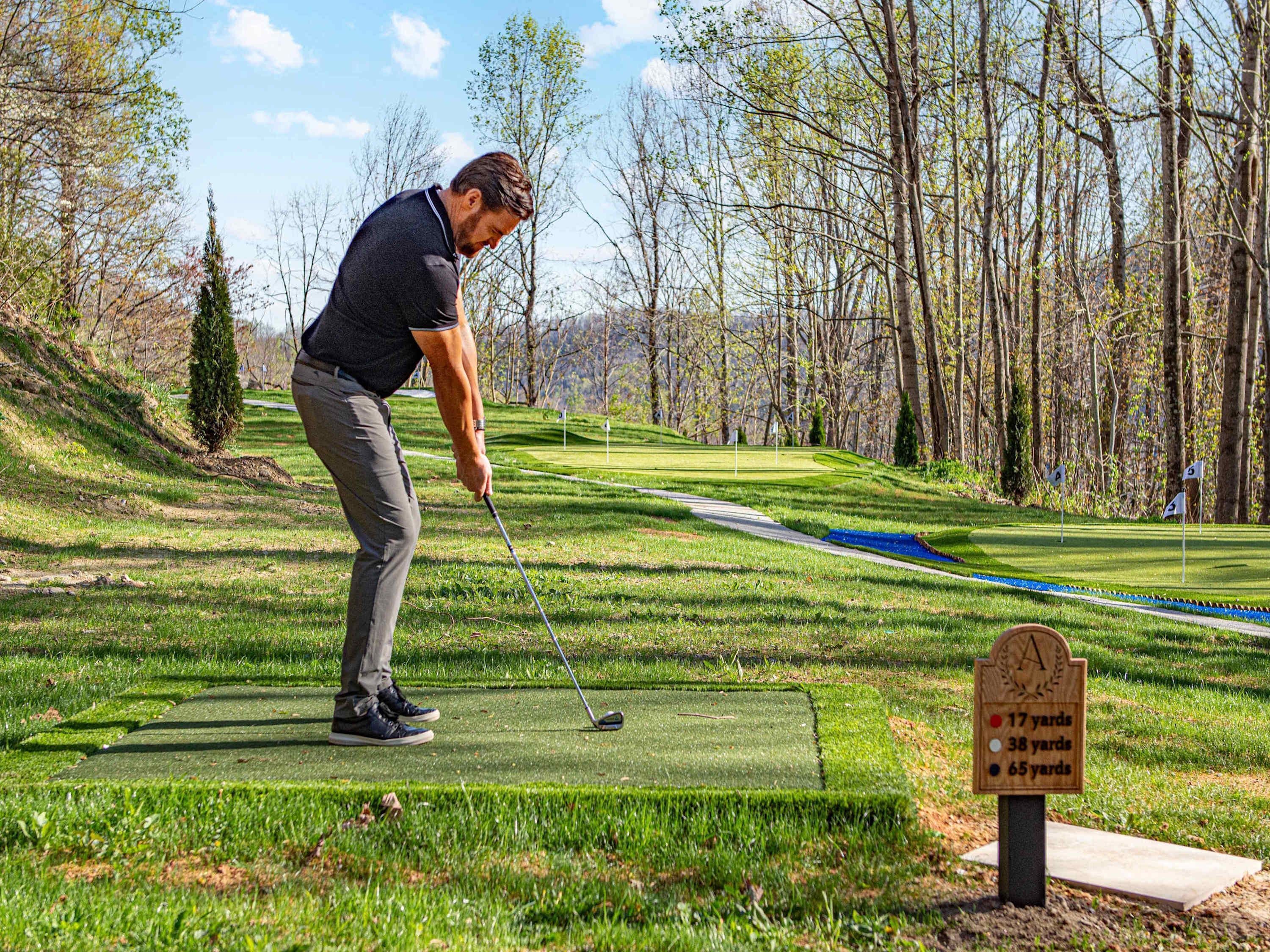 Una persona jugando golf en un campo bien cuidado con cielo despejado.