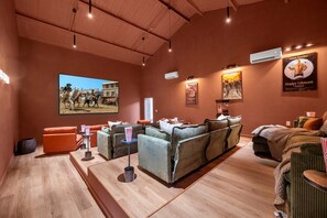 A cozy movie theater with a large screen, comfortable seating, popcorn containers, and movie posters on the walls. - Birdie Creek Ranch - Private Golf Course Resort (Driftwood)