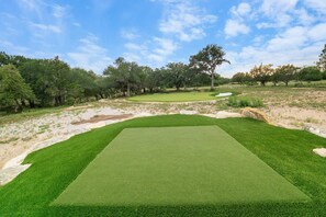 A golf course with a well-maintained green, sand bunkers, and trees in the background. - Birdie Creek Ranch - Private Golf Course Resort (Driftwood)