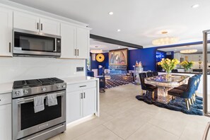 A modern kitchen with stainless steel appliances, a dining area with a round table and chairs, and a blue accent wall. - Luminosity Escape Pool Hot Tub Dog-friendly (Scottsdale)