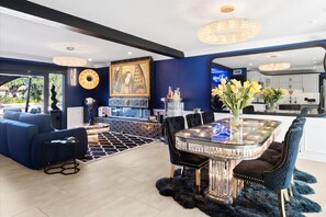 A modern interior with a dining area, sofas, a chandelier, and a large painting. - Luminosity Escape Pool Hot Tub Dog-friendly (Scottsdale)