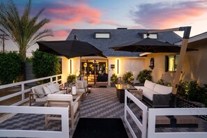 Eine Terrasse mit Sitzgelegenheiten im Freien, ein überdachter Eingang und Blick auf das Anwesen.