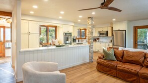 A modern kitchen with white cabinetry, a stone pillar, and a ceiling fan. - Prime Sequoia Stay Pool Hot Tub Sauna Views (Three Rivers)