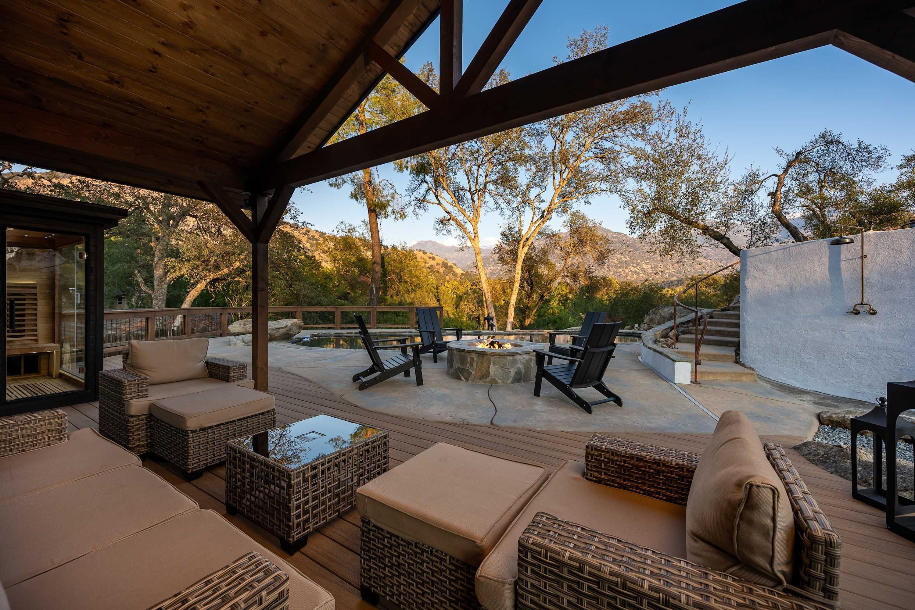 An outdoor patio with wicker furniture, a fire pit, and a view of a mountainous landscape.