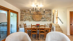 A dining area with a stone wall, wooden furniture, and a chandelier. - Prime Sequoia Stay Pool Hot Tub Sauna Views (Three Rivers)