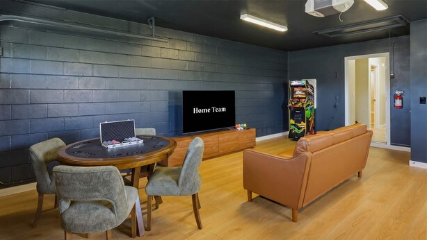 A room with a round table, two chairs, a sofa, a flat-screen TV, and a gaming machine. - Minutes to AMI Pool Game Room Sleeps 11 (Bradenton)