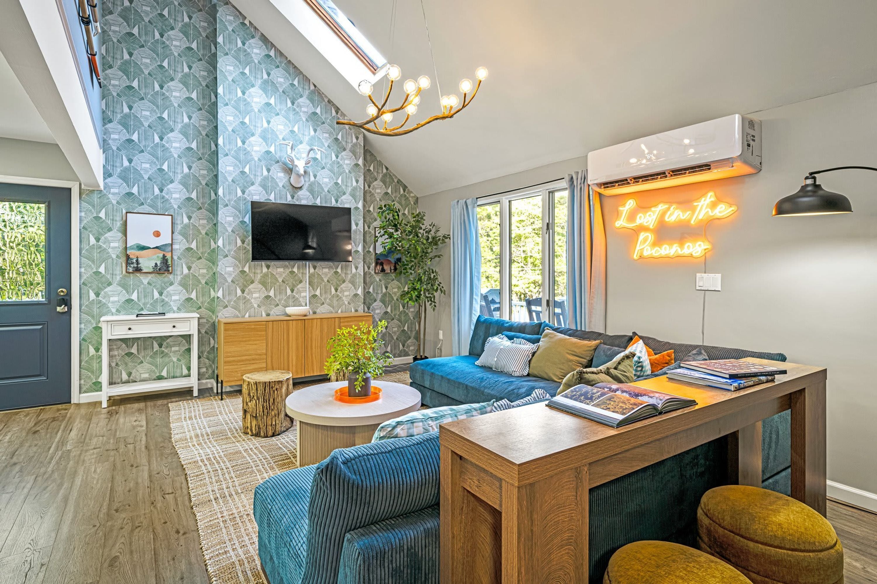 A modern living room with a large TV, a neon sign, and a cozy seating area.