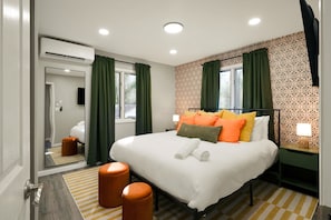 A modern hotel room with a large bed, green curtains, a patterned wallpaper, and a small side table with a lamp. - Poconos Lodge - Hot Tub Sauna Game Room Fire Pit (Long Pond)