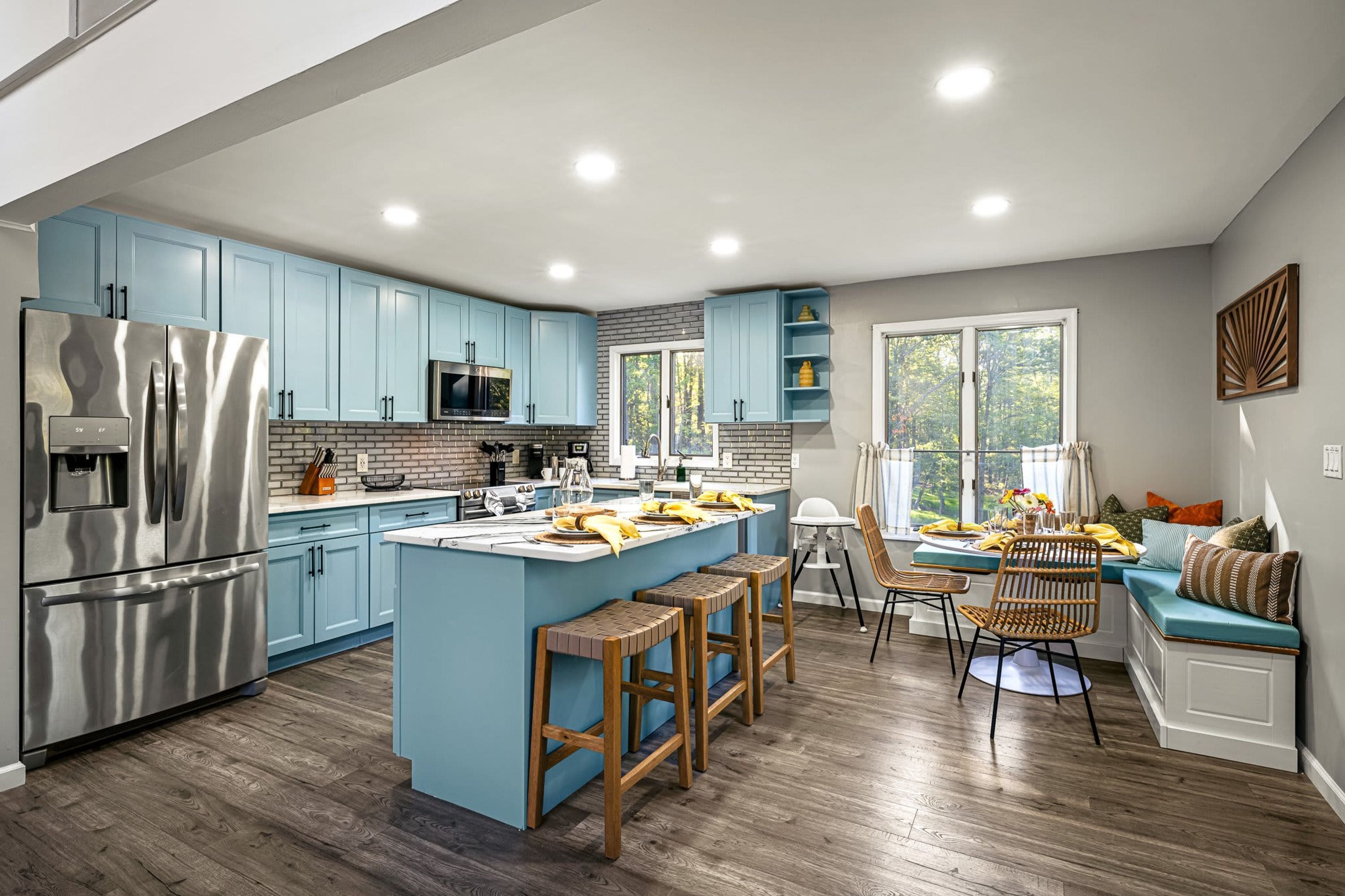 A modern kitchen with a central island, stainless steel appliances, and light blue cabinetry.