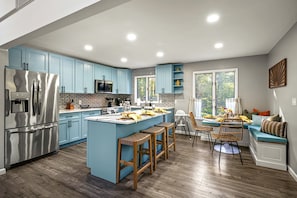 A modern kitchen with a central island, stainless steel appliances, and light blue cabinetry. - Poconos Lodge - Hot Tub Sauna Game Room Fire Pit (Long Pond)