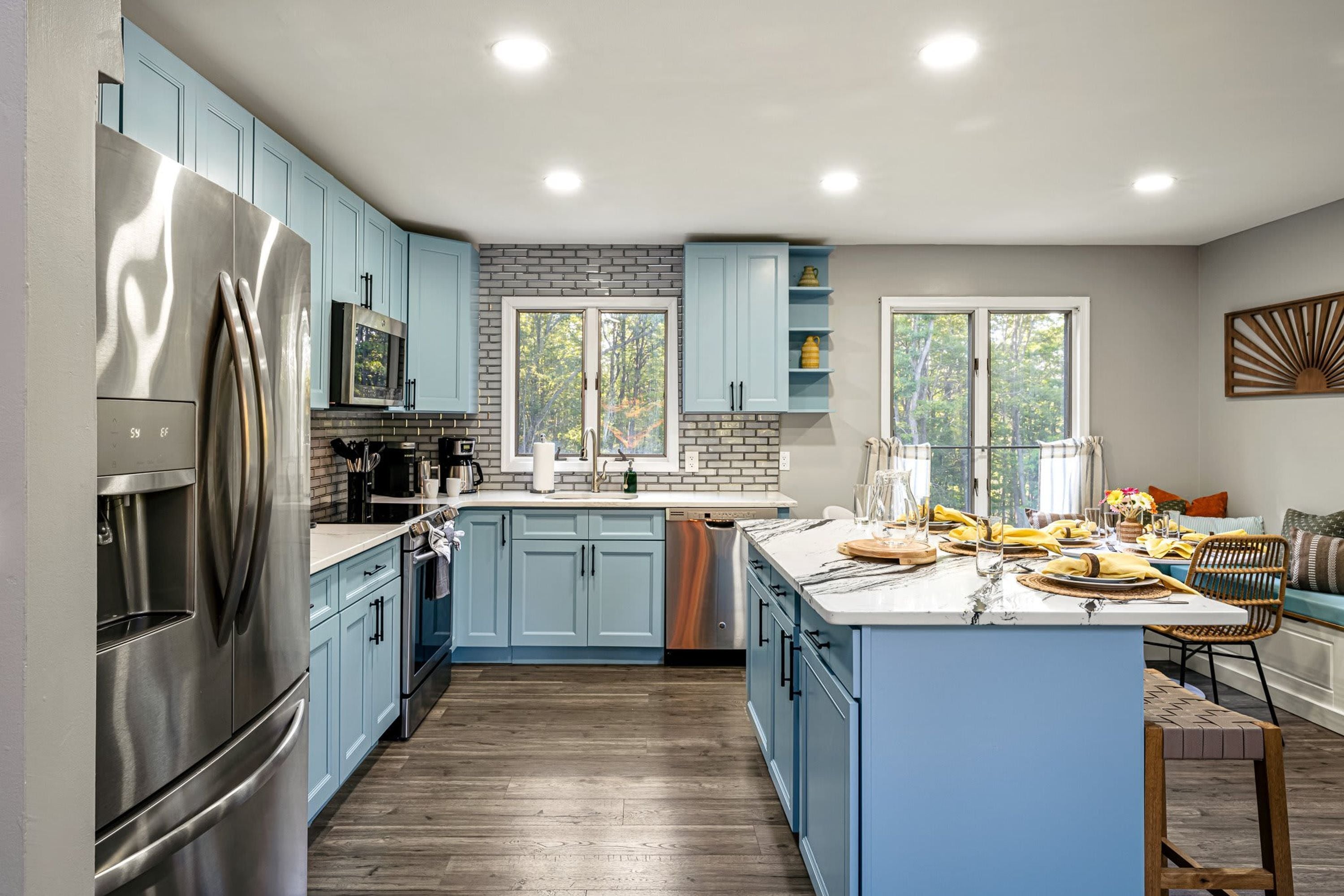 A modern kitchen with blue cabinets, stainless steel appliances, and a central island.