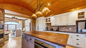 Une cuisine spacieuse avec des meubles de rangement en bois, un grand îlot central et un luminaire suspendu.