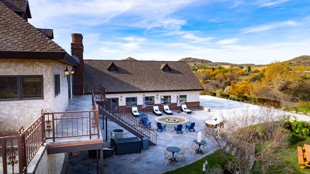 Une maison dotée d’un patio aménagé avec un espace salon extérieur et un foyer.
