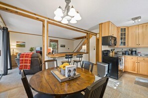 Eine geräumige Küche mit Holzausstattung, ein Essbereich mit rundem Tisch und eine Treppe, die in ein Obergeschoss führt.