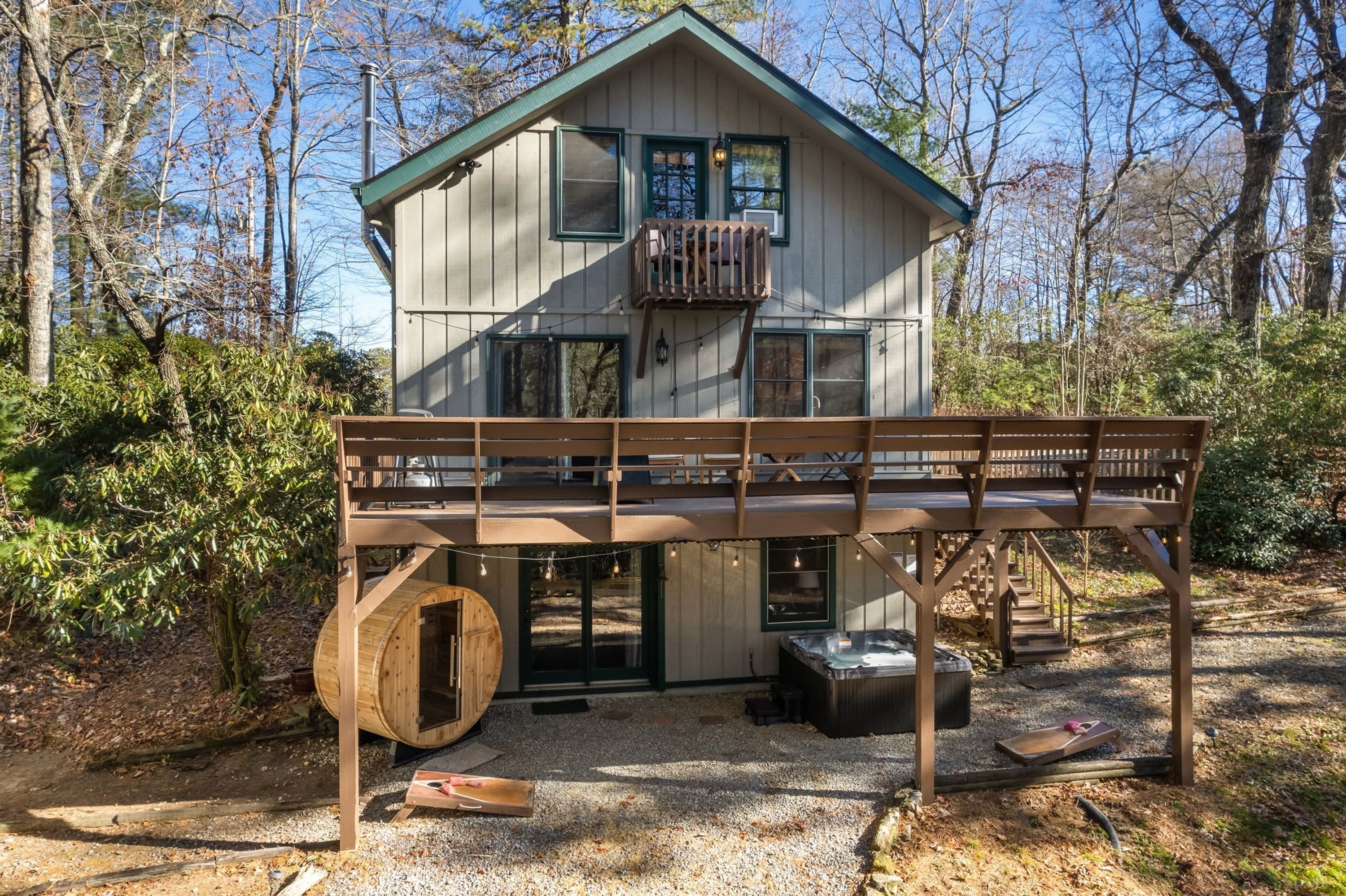 A cabin with a wooden deck, a hot tub, and a sauna.