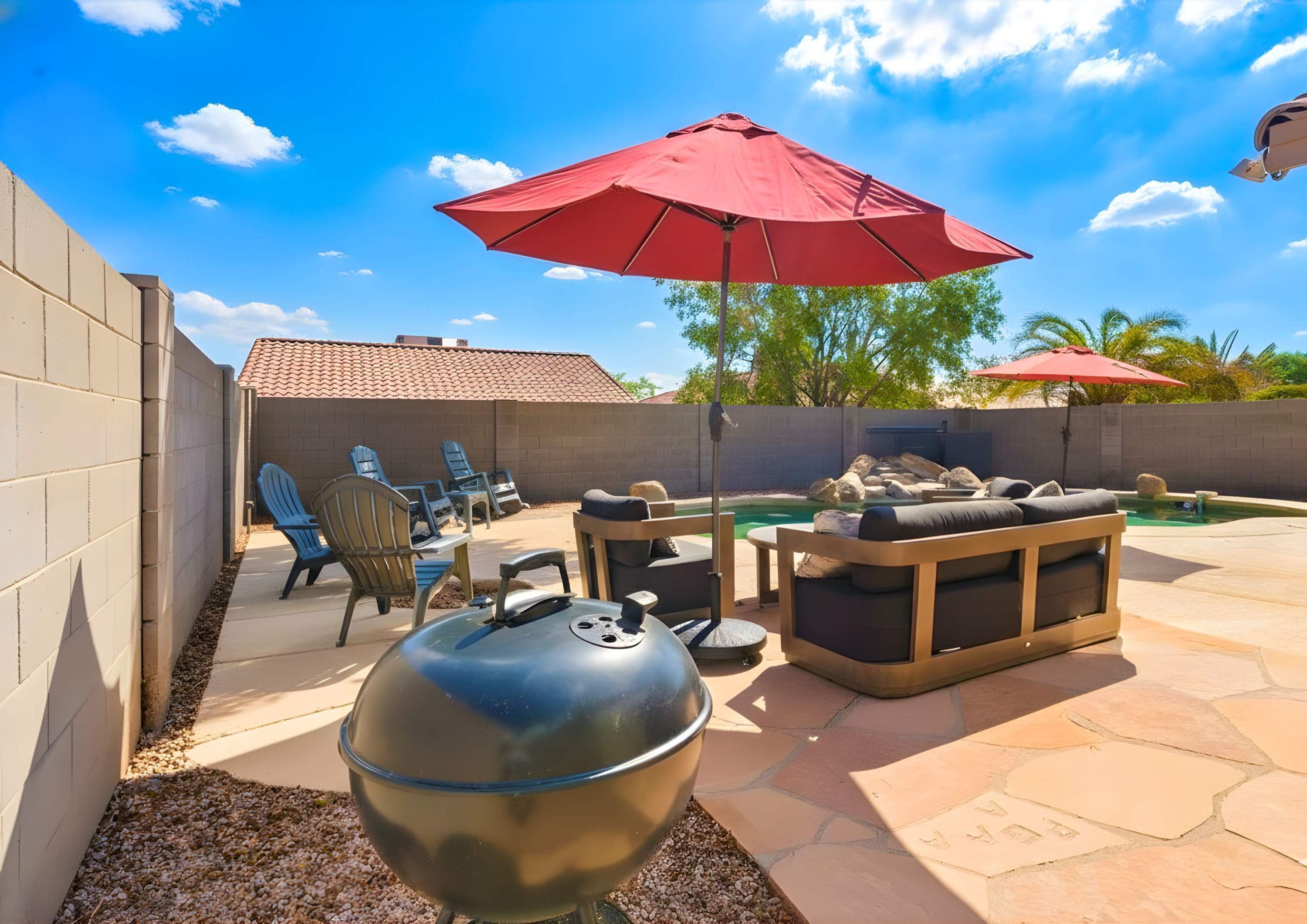 An outdoor patio with a barbecue grill, seating area, and a swimming pool.