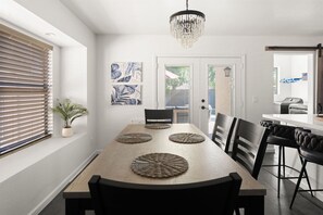 Un comedor con una mesa de madera, sillas negras y una araña.