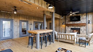 Un espacio interior amplio con piso de madera, una zona de bar, asientos y una chimenea.