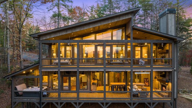Una cabaña de madera de dos pisos con varias habitaciones, un balcón y una chimenea.