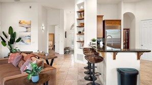 A modern kitchen with a bar area, a dining table, and a living room with a sofa and plants. - NEW Heated Pool Outdoor Fun Hottub Games More (Sedona)