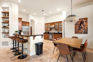 A modern kitchen with a central island, bar stools, a dining table, and a chandelier. - NEW Heated Pool Outdoor Fun Hottub Games More (Sedona)