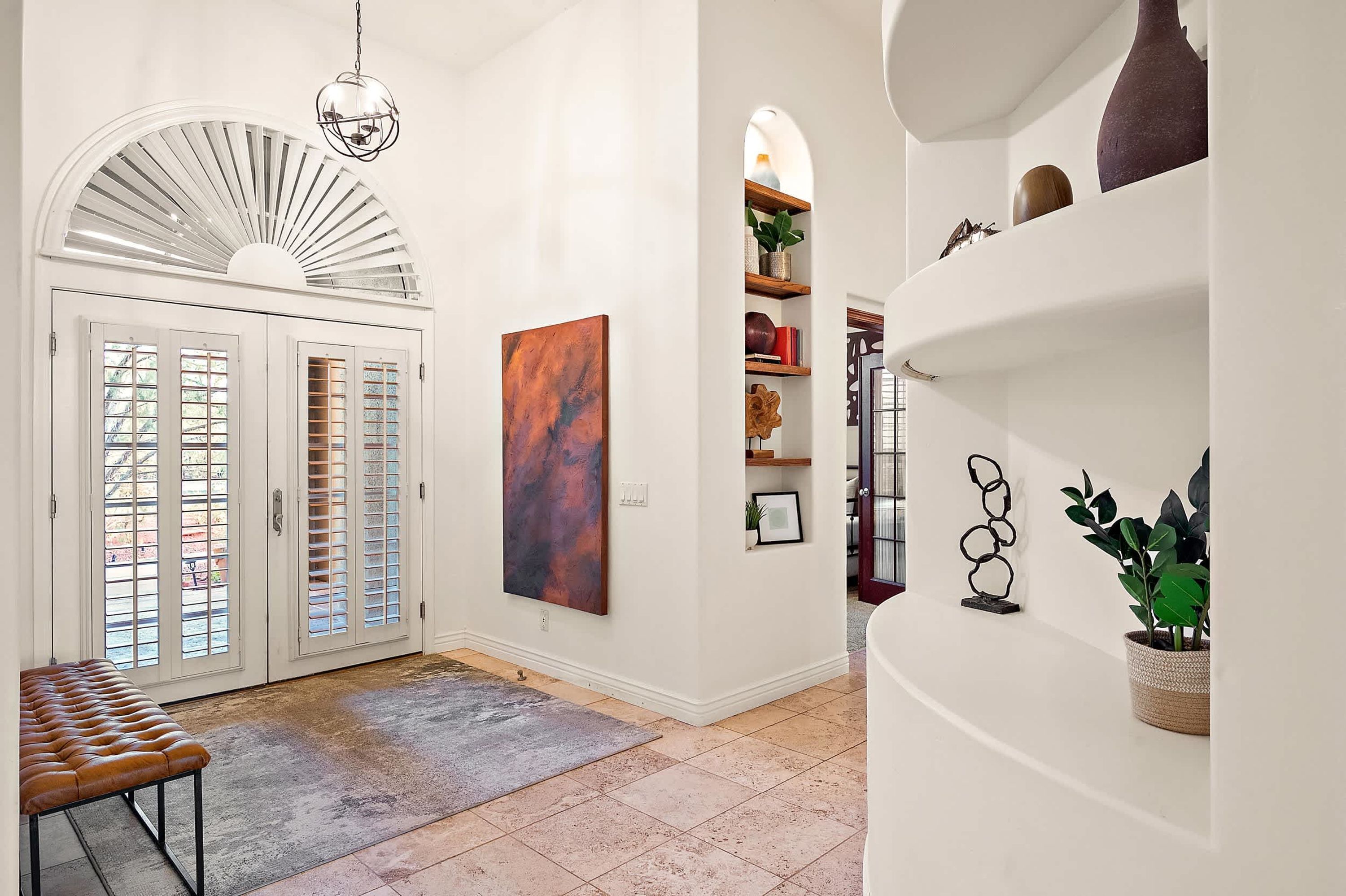 A hallway with a bench, a large abstract painting, and a staircase leading to another level.