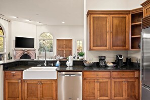 A modern kitchen with wooden cabinets, a stainless steel refrigerator, and a built-in dishwasher. - NEW Heated Pool Outdoor Fun Hottub Games More (Sedona)