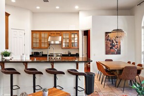 A modern kitchen with a central island, bar stools, a dining table with chairs, and a chandelier. - NEW Heated Pool Outdoor Fun Hottub Games More (Sedona)