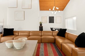 A modern living room with a brown leather sectional sofa, a coffee table, and a striped rug. - Family-friendly Getaway Hot Tub View EV Chrg (Flagstaff)