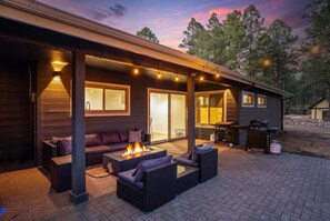A covered outdoor patio with a fire feature, seating, and a grill area. - Family-friendly Getaway Hot Tub View EV Chrg (Flagstaff)