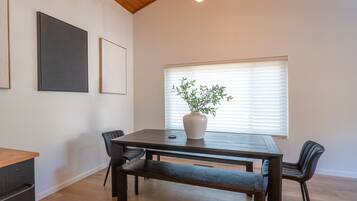 A dining area with a wooden table, benches, and a potted plant.