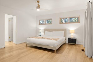 A bedroom with a bed, bedside tables, a ceiling fan, and windows. - Family-friendly Getaway Hot Tub View EV Chrg (Flagstaff)