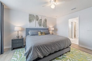 A bedroom with a bed, bedside tables, a ceiling fan, and a door leading to a bathroom. - Mins Away From Theme Parks Resort Access Pool (Davenport)