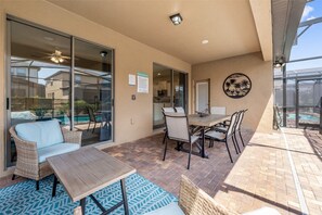 Eine Terrasse mit Tisch und Stühlen, Blick auf einen Pool und einer an der Wand befestigten Dekotasse.