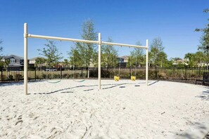A playground with a sand surface, metal swings, and a black fence. - Mins Away From Theme Parks Resort Access Pool (Davenport)