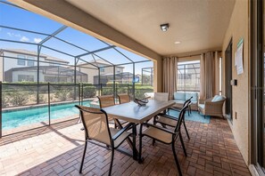 A covered patio with a pool, outdoor furniture, and a view of neighboring houses. - Mins Away From Theme Parks Resort Access Pool (Davenport)